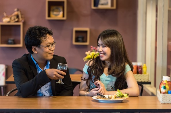 Man and woman sat at restaurant table looking at each other and smiling