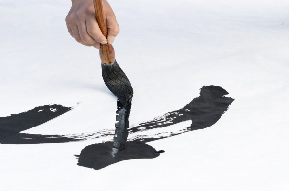 Hand holding brush writing Chinese calligraphy